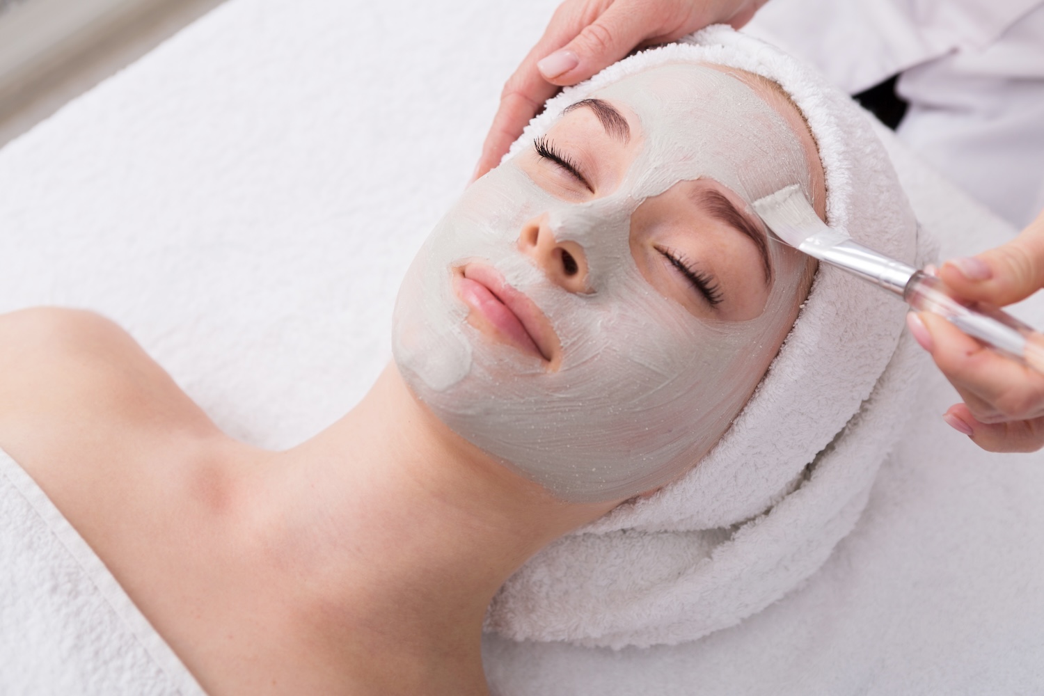 aesthetician applying a facial mask with a brush during a relaxing Circadia skincare treatment