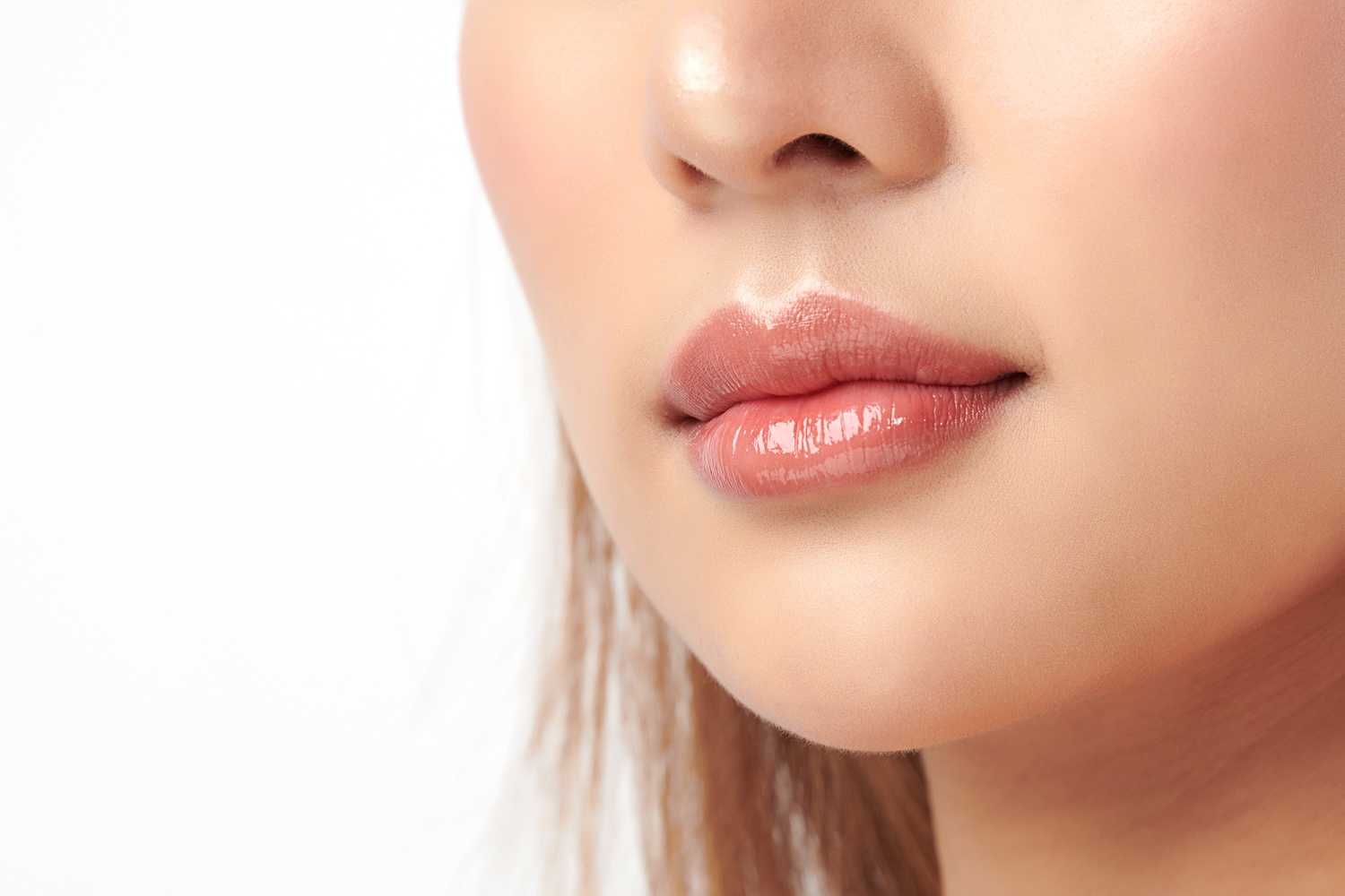 close-up of a woman’s glossy lips and lower face against a white background