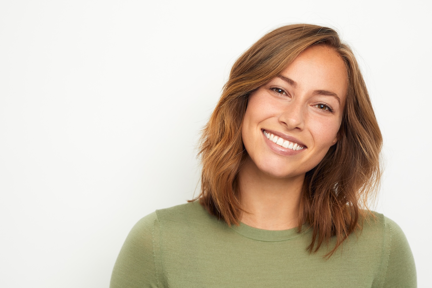 woman smiling and looking at the camera against a plain light background
