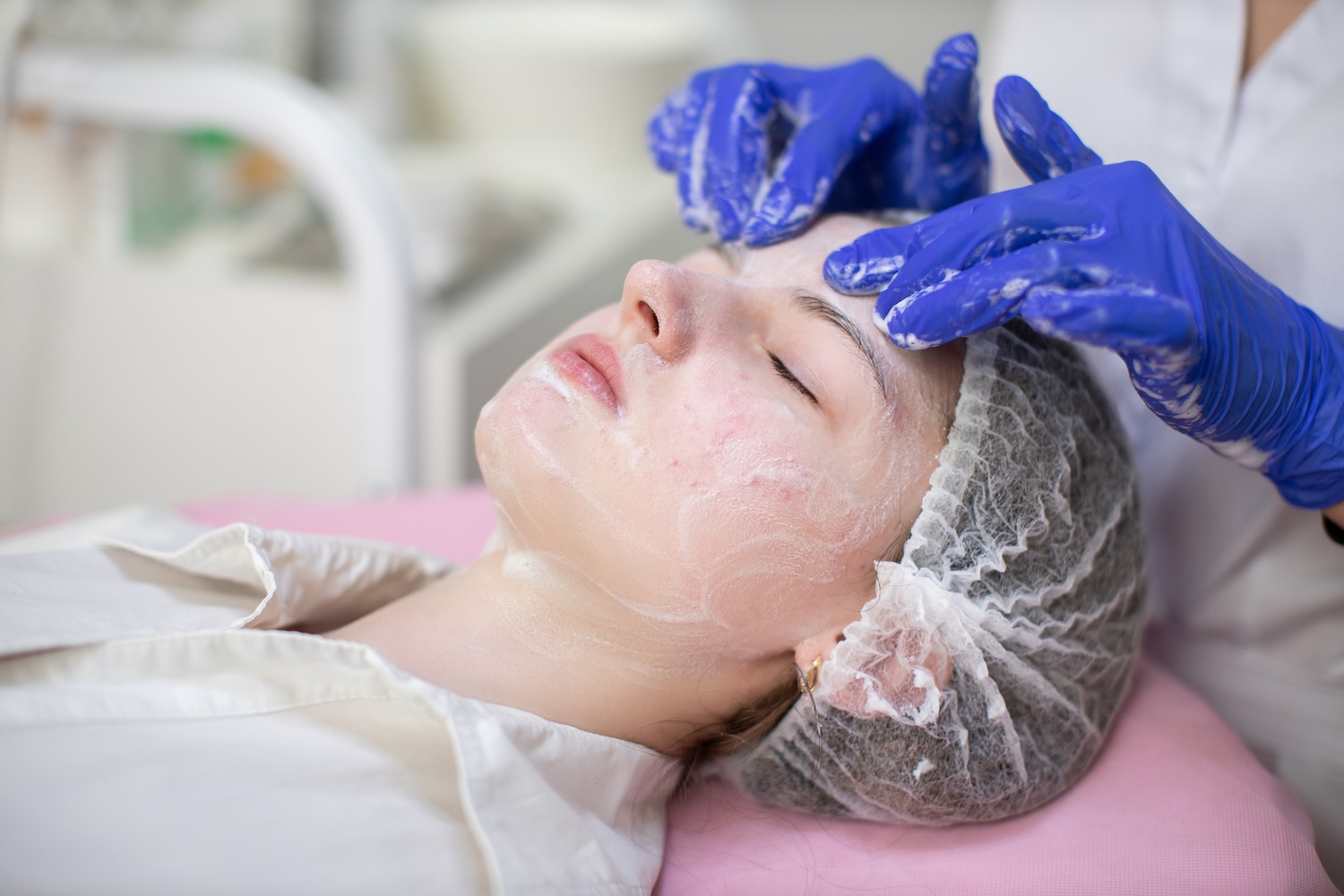 a teen receiving a deep cleansing facial as a skincare professional massages a foaming mask into the skin