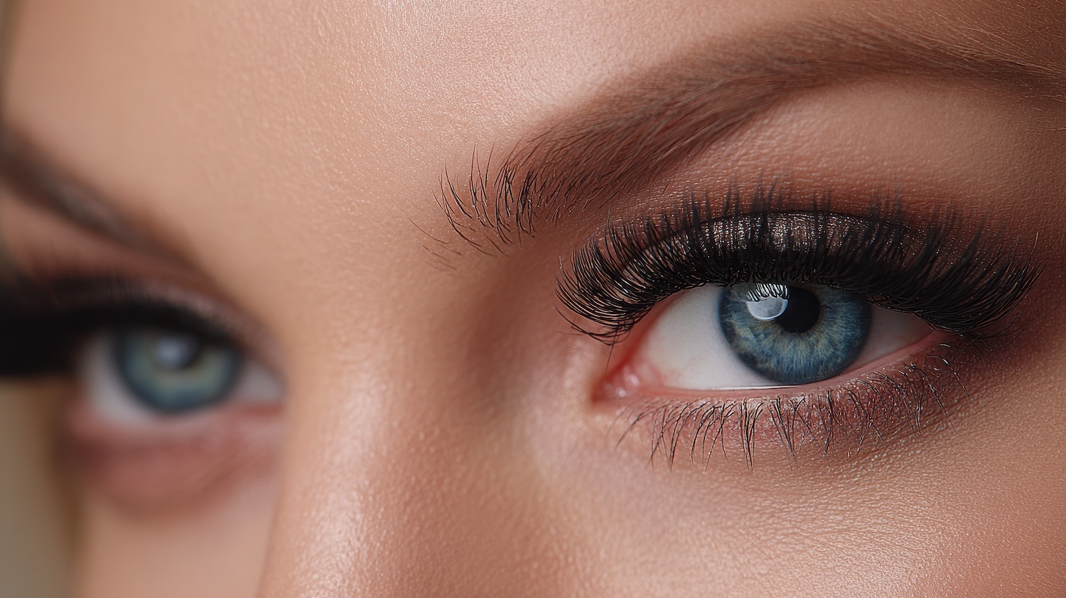 Close-up of blue eyes with long, dark eyelashes and subtle eye makeup visible on the eyelids.
