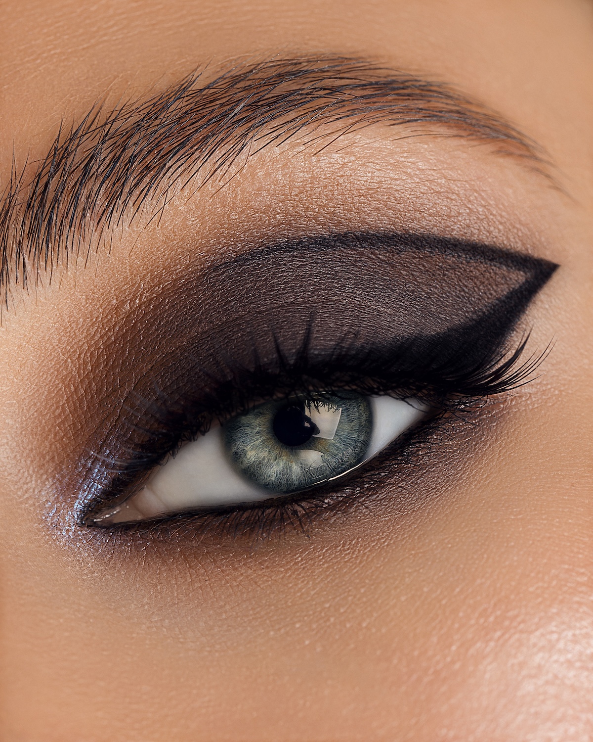 Close-up of a single eye with dark smoky eyeshadow, winged eyeliner, and defined eyebrow.